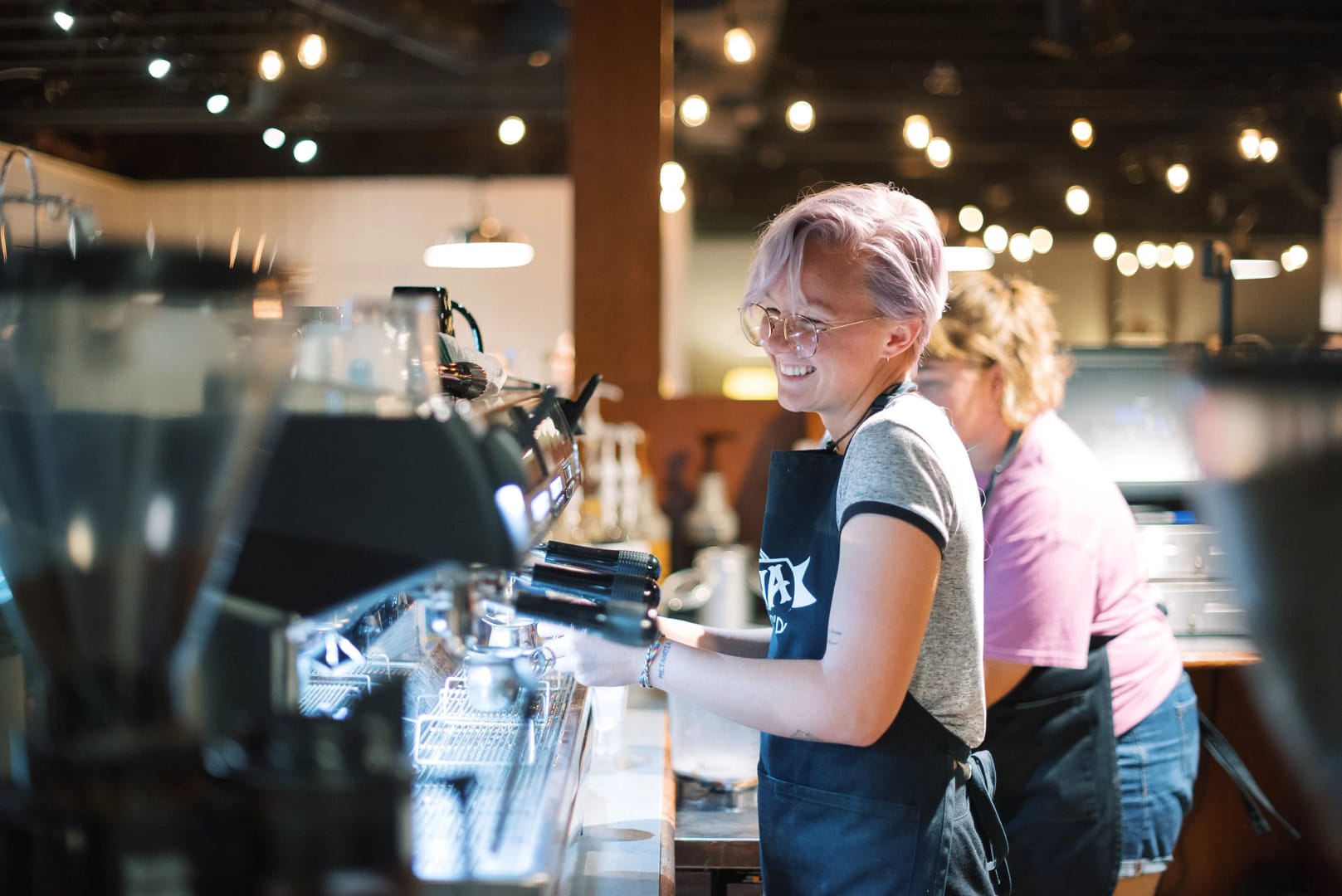 Smiling student makes coffee behind bar at Mocha Joe's.