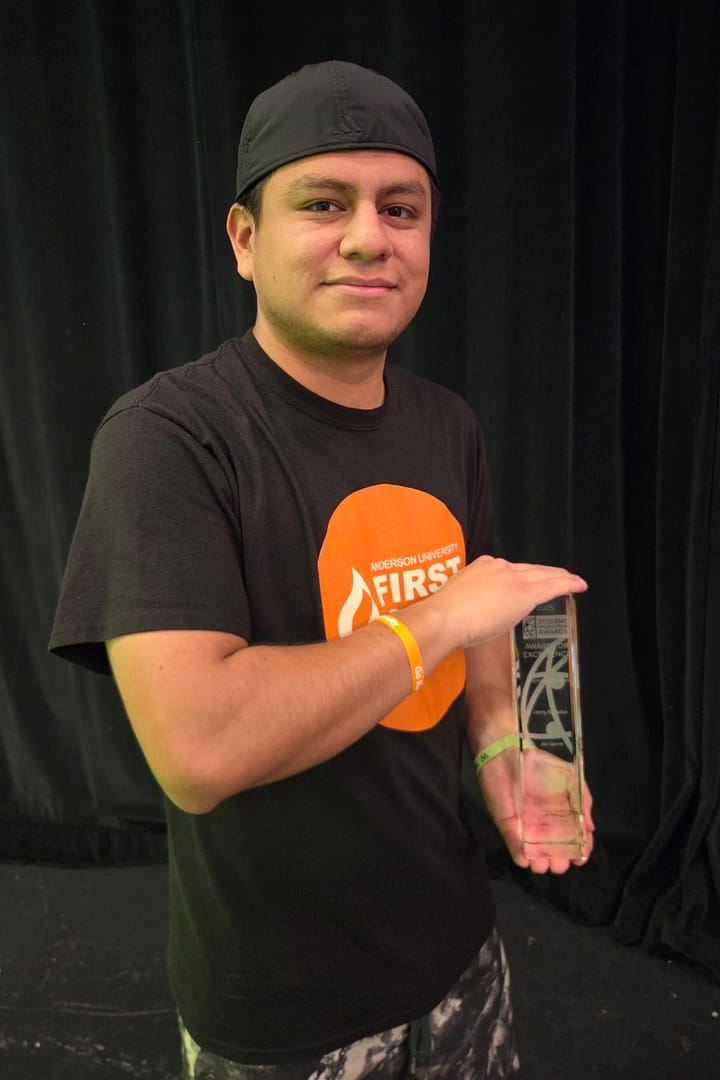 Jonny holds his "crystal pillar" trophy. 
