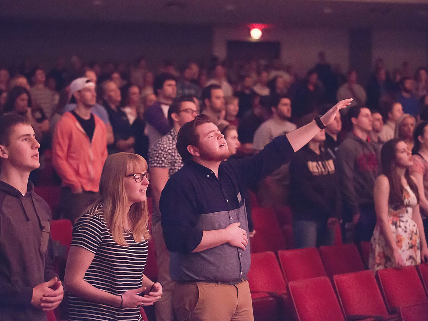 view of worshippers during chapel singing and lifting hands