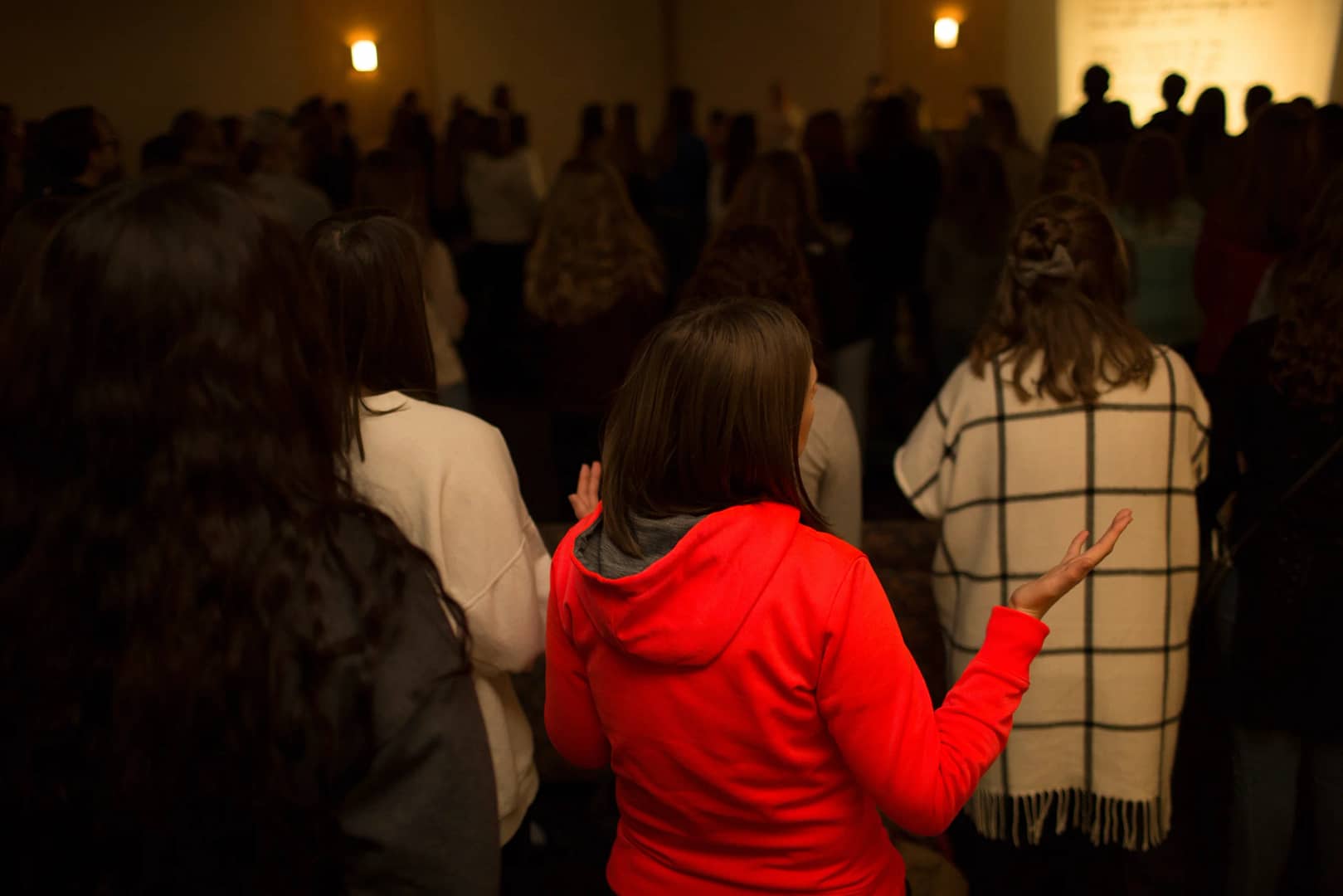 students are seen from behind worshiping together