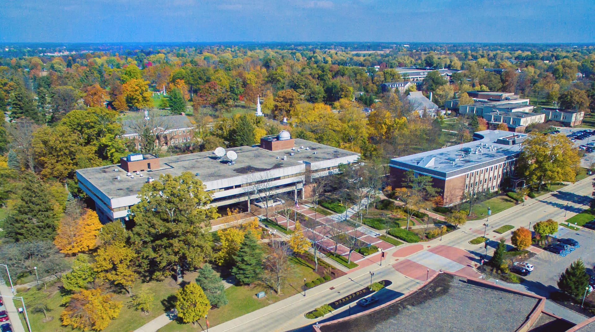 aerial view of campus with many buildings amidst fall trees