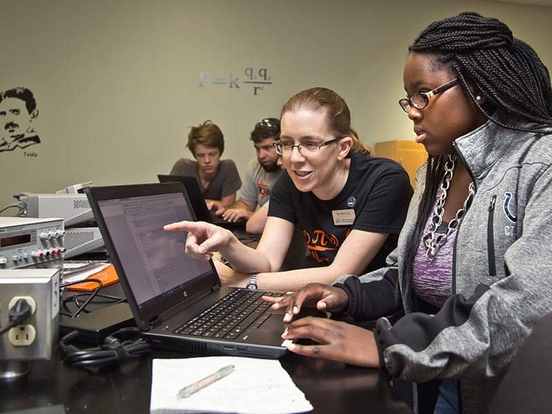 a female professor works in an electronics lab with a young female student